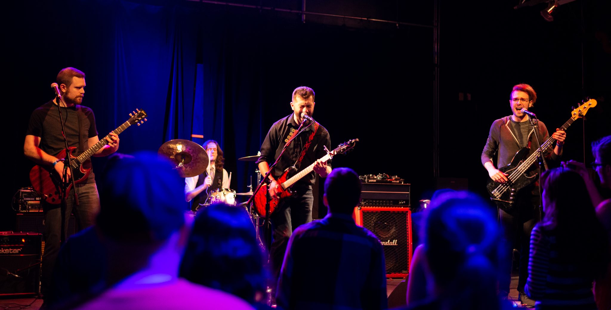 A wide angle image of Midnight Notion on stage at The Garage with a full crowd in the foreground.