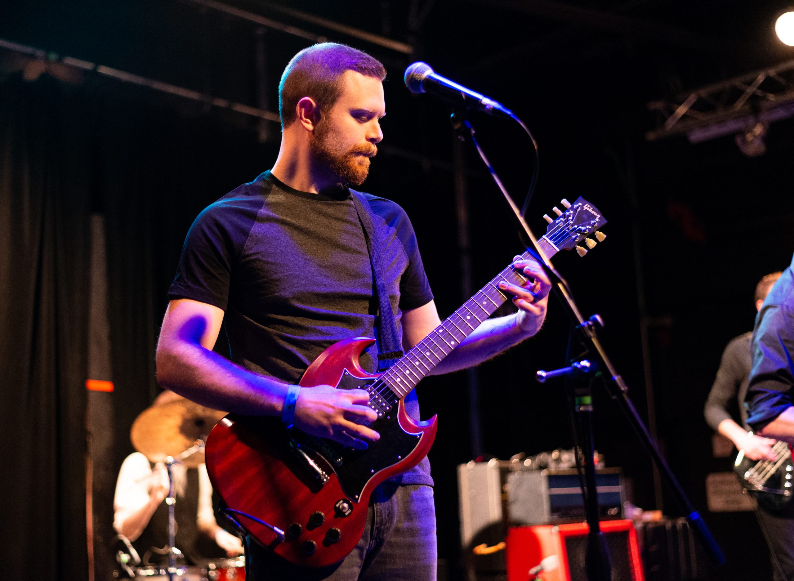 Chris Ragnacci playing a red guitar on stage at The Garage.